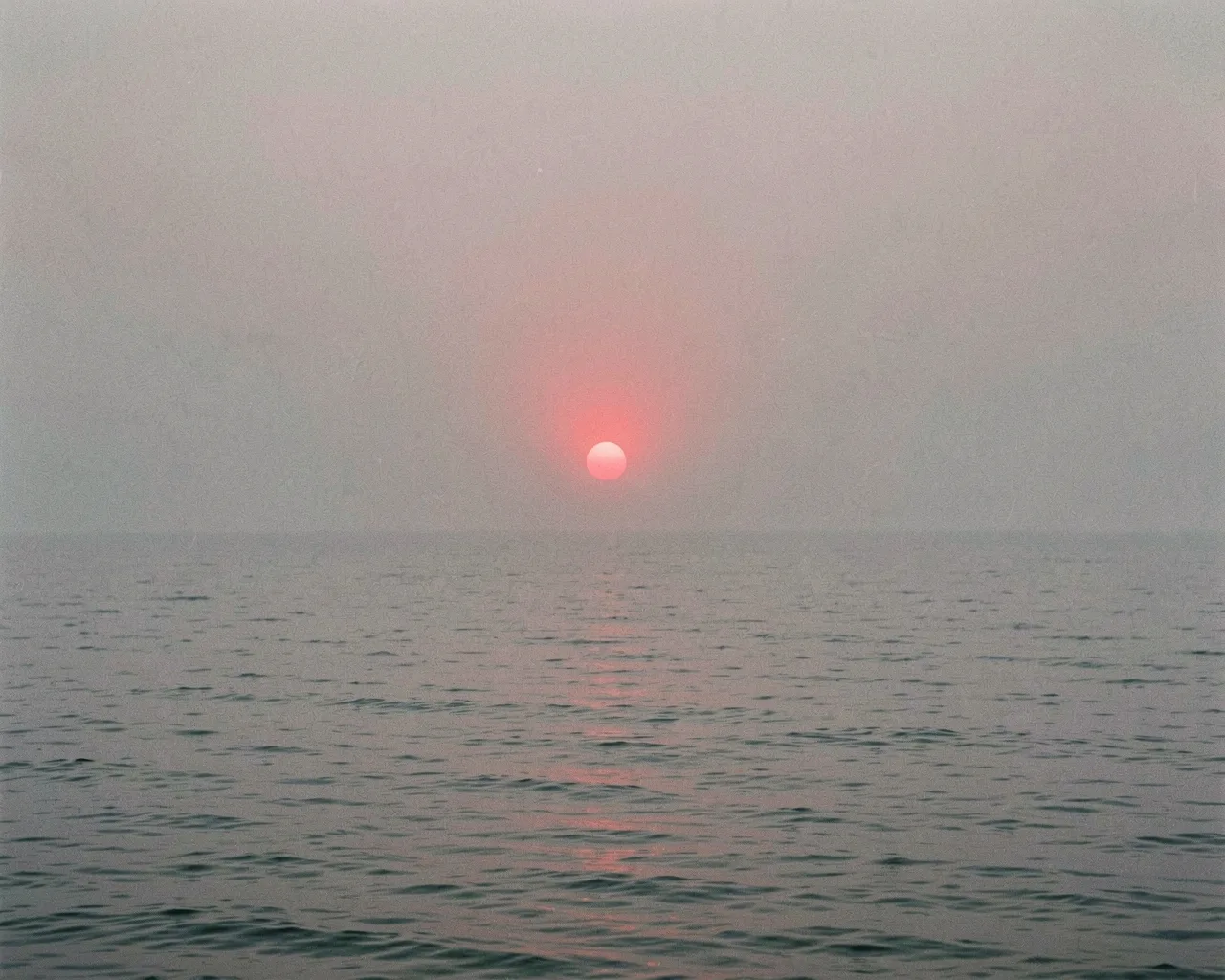A red sun low over a calm grey sea