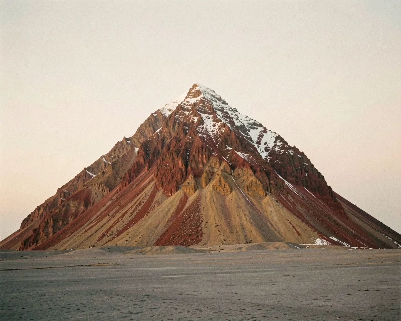 A red rock mountain over a grey plain