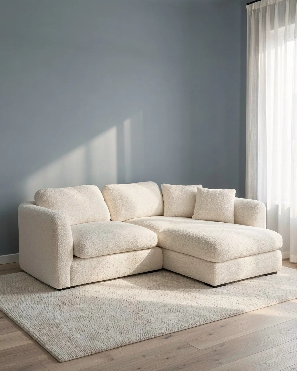 A cream bouclé corner sofa on a wool rug