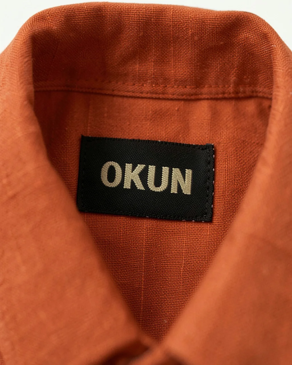 The black Okun label sewn inside a rust linen collar