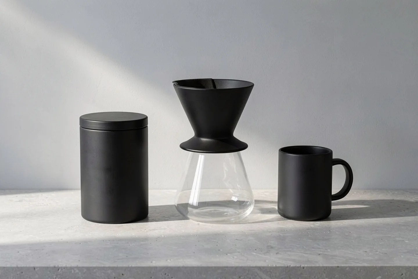 The coffee set in black: tin, dripper on a glass carafe, and mug