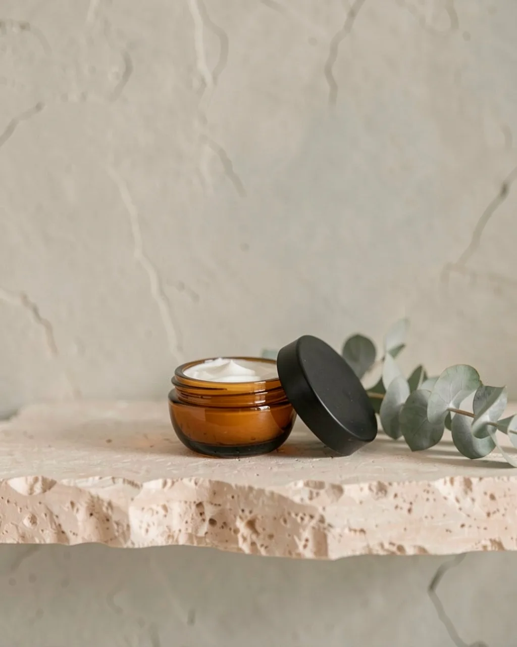 The hand cream in a small amber pot