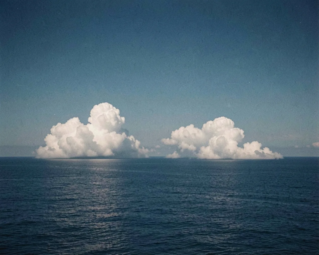 White clouds low over a dark blue sea